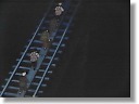 [ The travel-weary group makes a perilous trek across a tall rail bridge. ]
